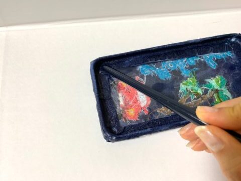 スマホケースの内側を、絵具の柄の先端で押す画像